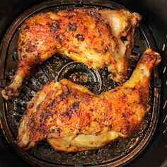 two pieces of chicken cooking in an air fryer