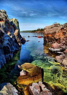 the water is crystal blue and clear with rocks on both sides, and boats in the distance