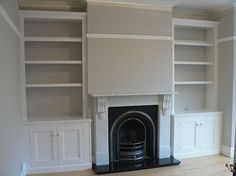 an empty living room with built in bookshelves and fireplace