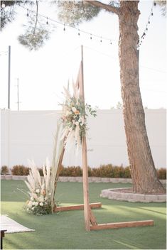 an outdoor ceremony setup with flowers and greenery on the grass in front of a tree