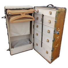 an open suitcase with clothes hanging out of it's doors and the lid opened