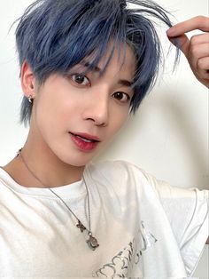 a young man with blue hair is posing for the camera