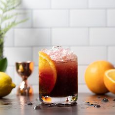 a drink with oranges and ice in front of some lemons on the table