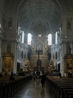 the inside of a church with pews and decorated christmas trees in front of it