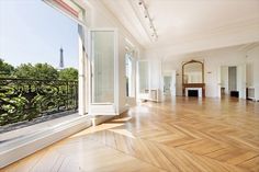 an empty living room with wood floors and large windows