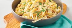 a bowl filled with pasta on top of a wooden cutting board