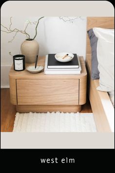 a nightstand with a book, bowl and candle on it next to a white rug