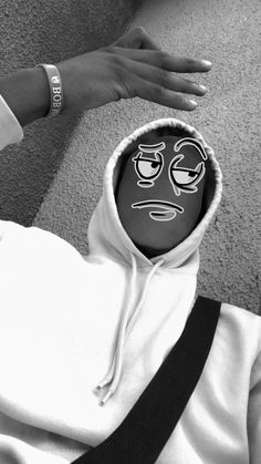 a black and white photo of a person wearing a hoodie with a face painted on it