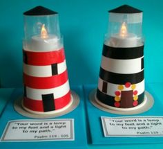 two small lighthouses are on display with words written below the lights and candles in front of them