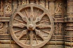 an intricately carved stone wheel on the side of a building with carvings around it