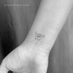 a black and white photo of a hand with a small finger tattoo on the wrist