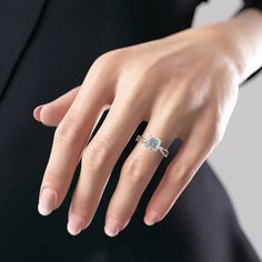 a woman's hand with a diamond ring on her left hand, wearing a black suit