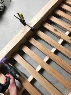 a person is working on a wooden bed frame with tools and screwdrivers next to it