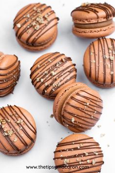 chocolate macaroons are lined up on a white surface