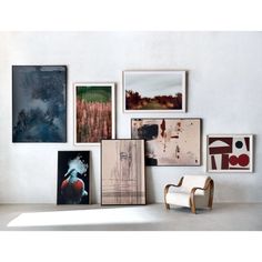 a white chair sitting in front of a wall filled with pictures and paintings on it