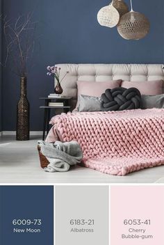 a bedroom with blue walls, pink and gray bedding, grey throw pillows, white headboard