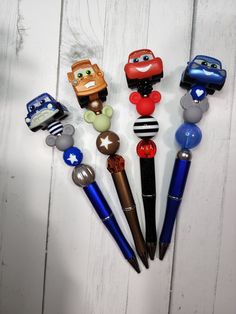 five different pens with cartoon characters on them sitting in front of a white wooden wall