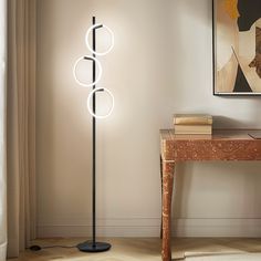 a floor lamp with three circular lights on it next to a small table and chair