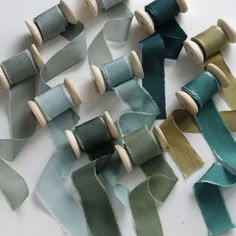 several different colored spools of thread on a white surface with wooden pins in the middle