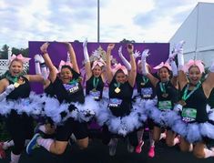 a group of women in black shirts and pink tutus posing with their arms up