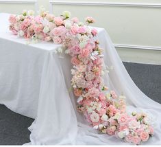 a table with flowers on it and a white cloth draped over the table for an elegant look