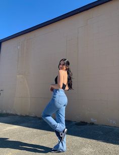 a woman leaning against a wall with her back to the camera