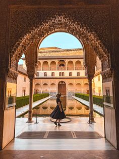 a woman is walking through an archway in the middle of a courtyard with many arches