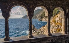 an outdoor area overlooking the ocean with stone pillars and arches on each side, looking out to sea