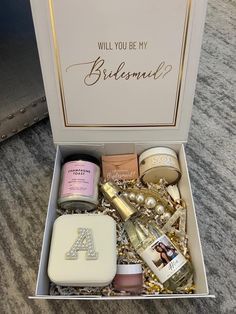 an open box containing personal care items on a carpeted floor with the words, will you be my bridesmaid?