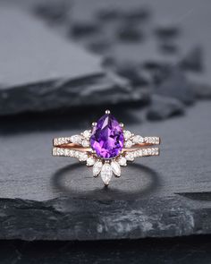 a ring with an amethorate and diamonds on it sitting on top of a rock