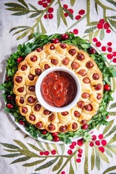 a platter filled with food on top of a white table covered in holly leaves