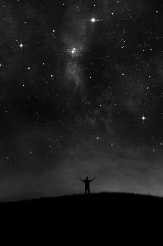 a person standing on top of a hill under the stars