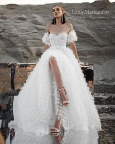 a woman in a white dress sitting on a rock