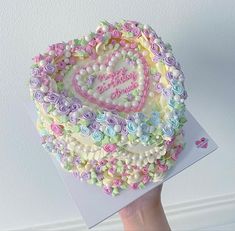 a hand holding a cake decorated with flowers