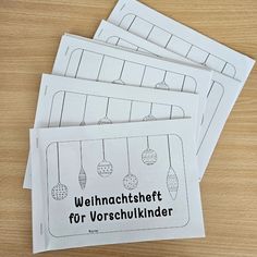 four german worksheets with christmas ornaments hanging from them on a wooden table top