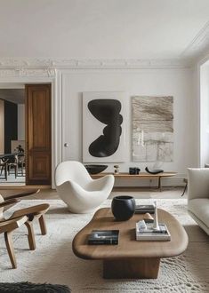 a living room filled with white furniture and art on the wall above it's coffee table