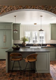 two chairs are sitting in front of the kitchen island with an archway leading into it