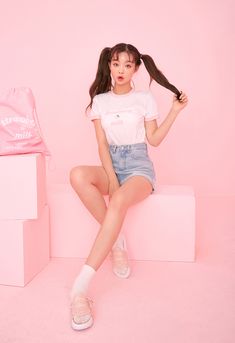 a young woman sitting on top of a pink box with her hair in the air