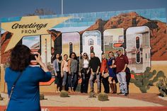 a group of people standing in front of a wall painted with the words greetings from arizona