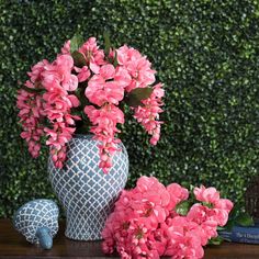 pink flowers are in a blue and white vase next to books on a wooden table