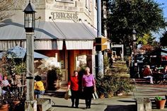 two women walking down the sidewalk in front of a store