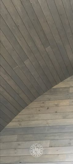 a clock on the side of a building with wood flooring and wooden walls behind it