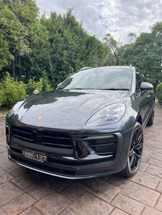 a black porsche cayen is parked in front of some trees