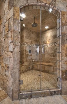 a walk in shower sitting inside of a bathroom next to a stone tiled wall and floor