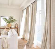 a living room filled with white furniture and curtains