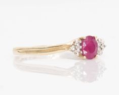 Item Description: This high mounted statement ring is full of color and character. The beautiful red oval ruby in the center is mounted in a four-prong frame slightly higher than the rest of the diamonds. At each side there is a tiny diamond accent with a few prong cluster. The ring's shoulder features a swanky dainty design with the appearance of two rows, but in fact it is an indentation in the yellow gold frame that goes half way down the shank. Side profile shows a high cathedral style setti Oval Red Diamond Ring With Accents, Red Oval Diamond Ring With Accents, Antique Handmade Oval Ruby Ring, Luxury Vintage Oval Cabochon Ruby Ring, Oval Ruby Ring In 14k Gold, Art Deco Style, 14k Gold Multi-stone Oval Ruby Ring, Ruby Rings With Center Stone, Oval Cabochon Shape, Purple Band, Tiny Diamond