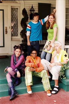 a group of young people sitting on the front steps of a house