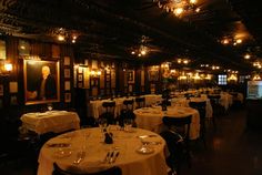 a dimly lit dining room with white tablecloths and dark wood paneled walls