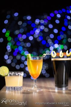 three different types of cocktails on a table with lights in the backgroud