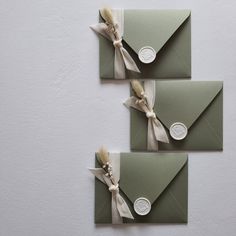 two envelopes with ribbons tied to them, one is green and the other is white